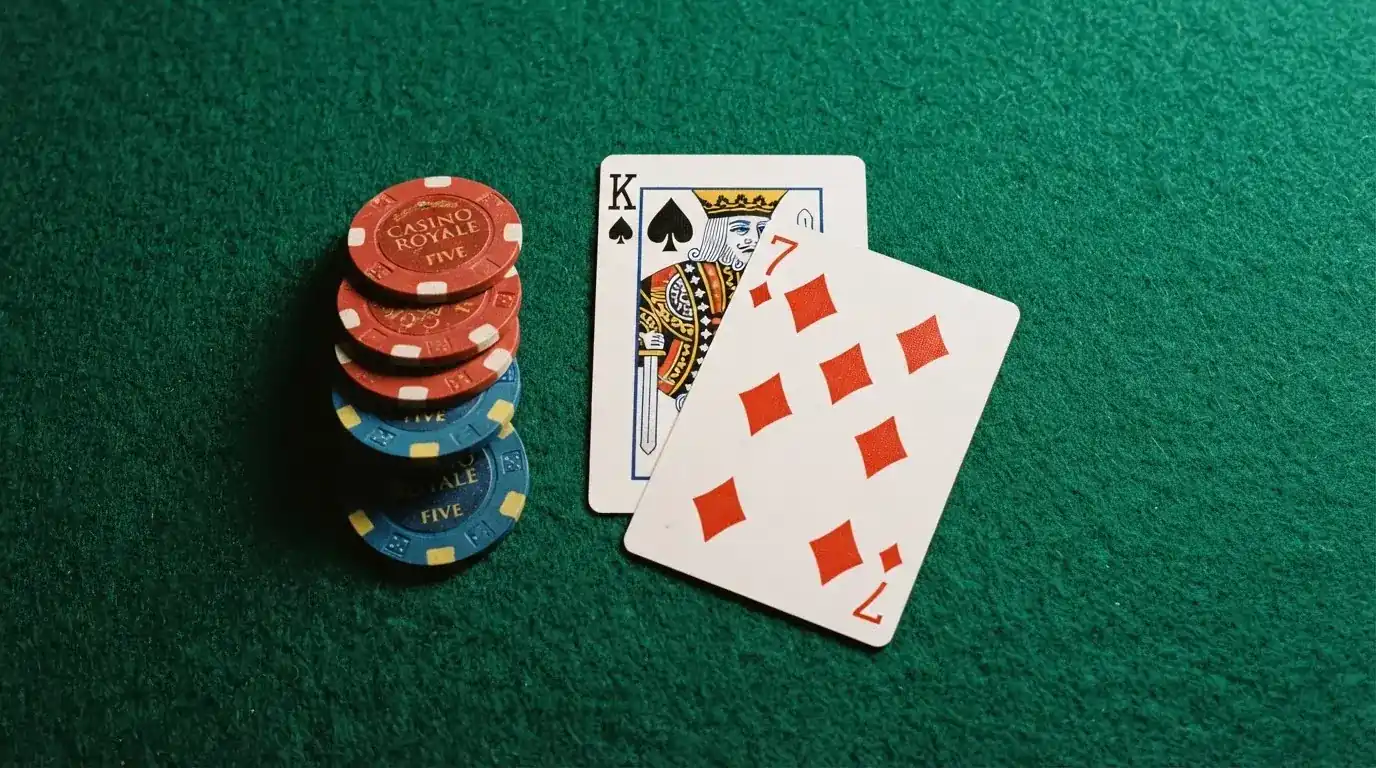 Vista cenital de una baraja de cartas y fichas de casino apiladas sobre una mesa de fieltro verde.